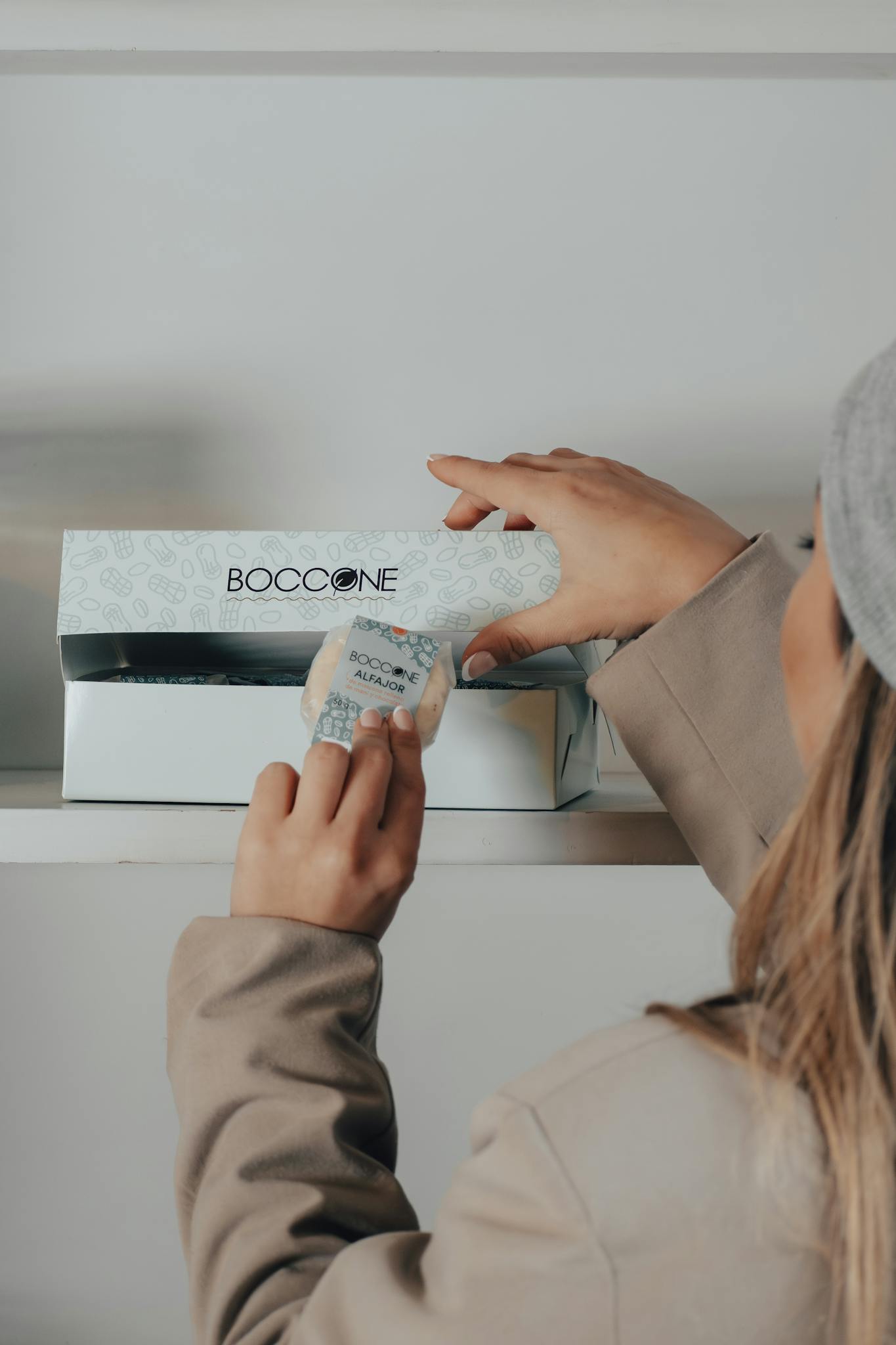A woman opening a Boccone box in a store setting, focusing on packaging.
