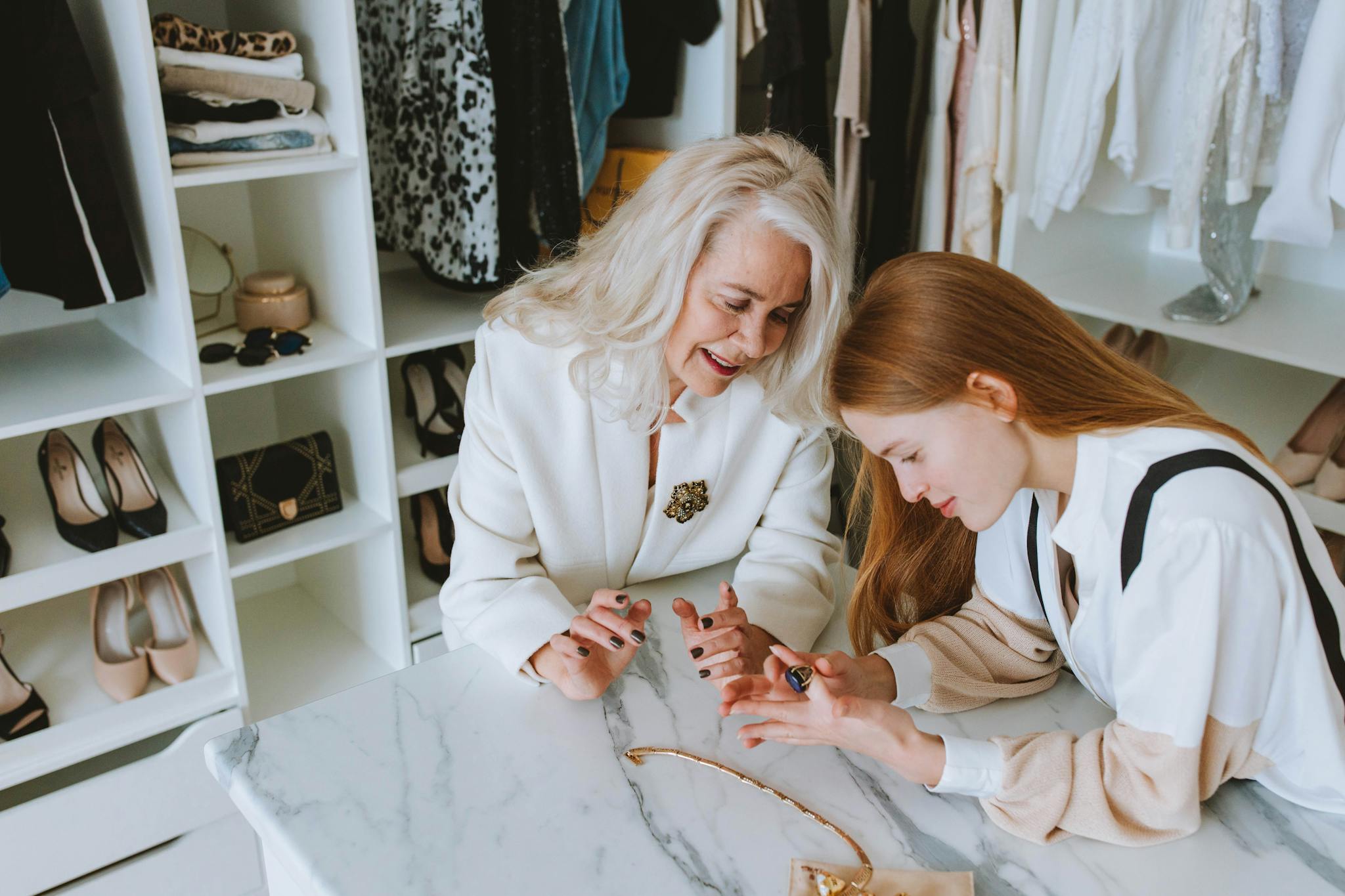 Two women exploring luxury jewelry in a stylish wardrobe setting.